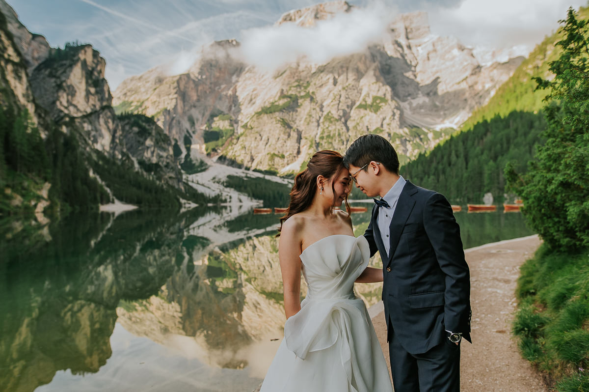 Bride and groom walking by the lake di Braies in Italian Dolomites