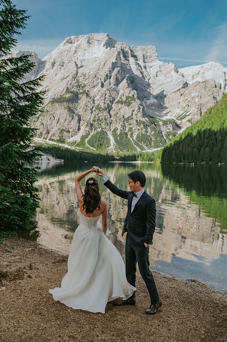 Bride and groom dancing by the lake Lago di Braies in Italian Dolomites
