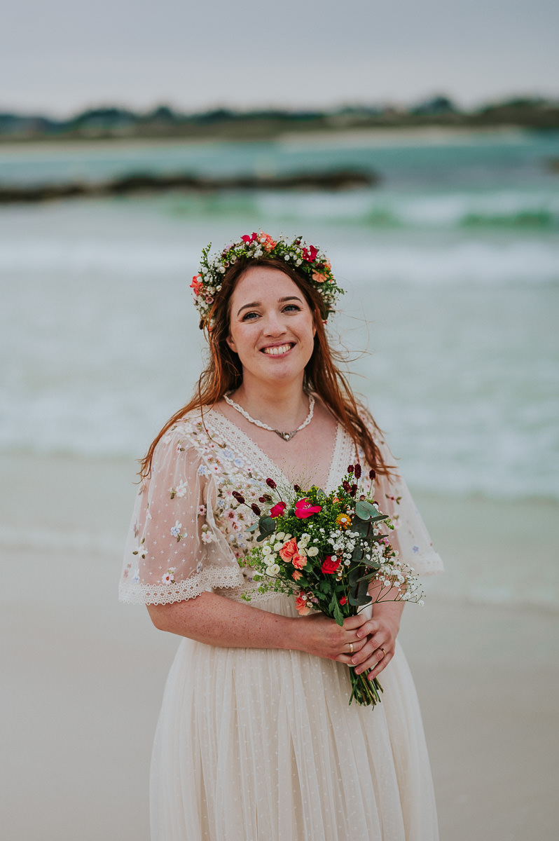 Nydelig brud med en blomster dekorert brudekjole og blomsterkrans i håret spaserer i turkis vann på bryllupsdagen sin i Haugesund