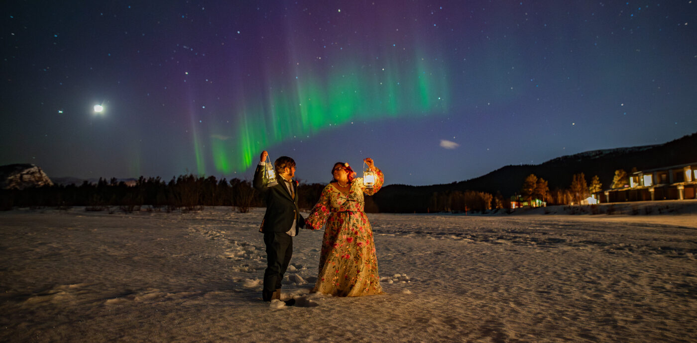 Northern lights wedding in Norway - bride and groom watching a beautiful Aurora borealis show outside of their mountain lodge in Alta Norway