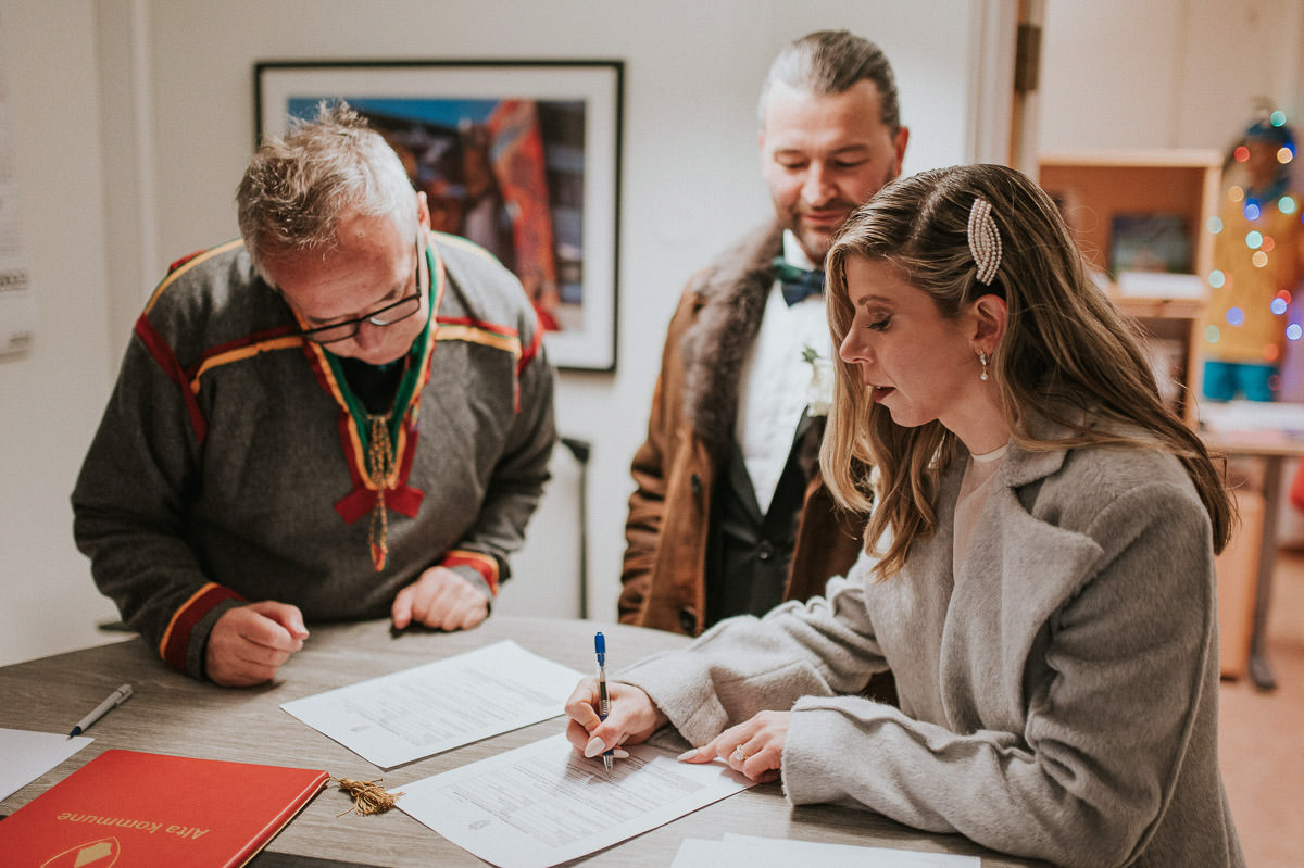 Bride and groom signing the papers after their legally binding elopement wedding in Alta Norway