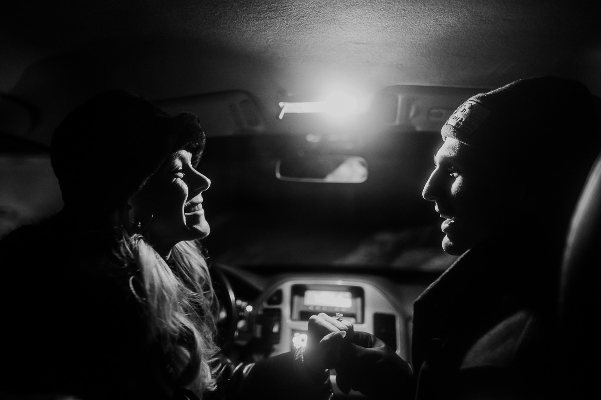 Black and white portrait of a couple sitting in the car - they just got engaged and look happy