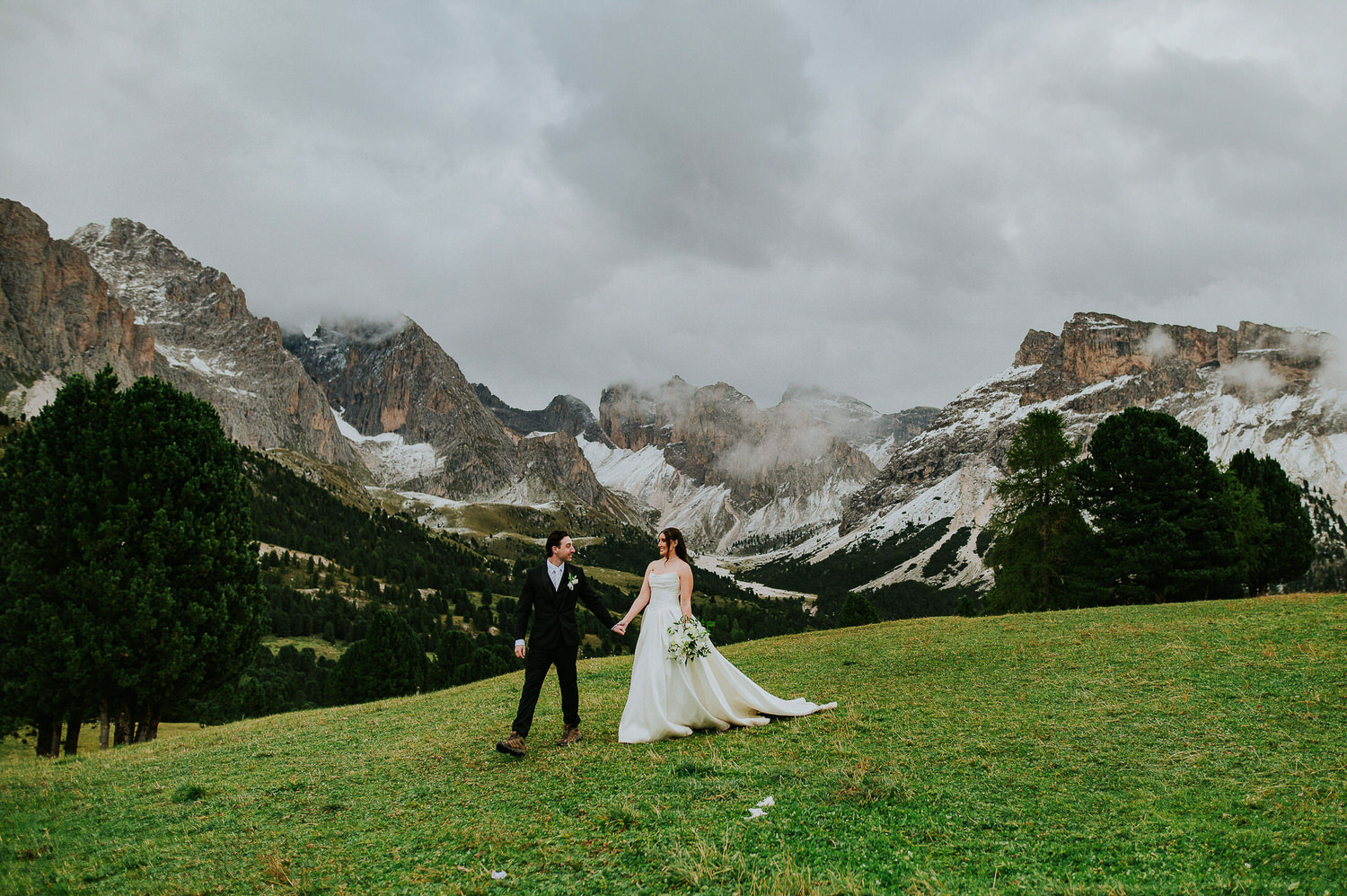 Bride and groom walking among stunning mountain landscapes in Italian Dolomites on the day of their adventure elopement