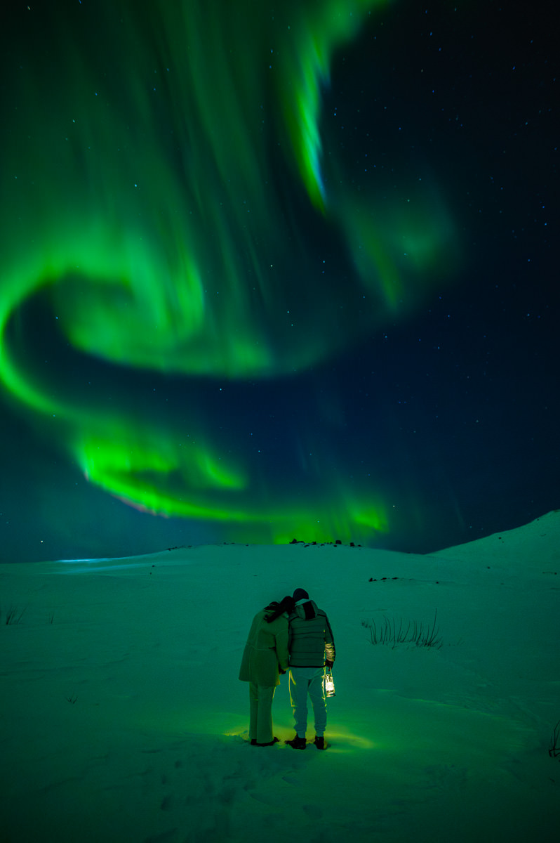 A couple watching aurora borealis after their surprise proposal in Tromsø Norway
