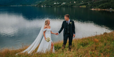 Et vakkert brudepar spaserer foran en fjord i Alta på bryllupsdagen sin