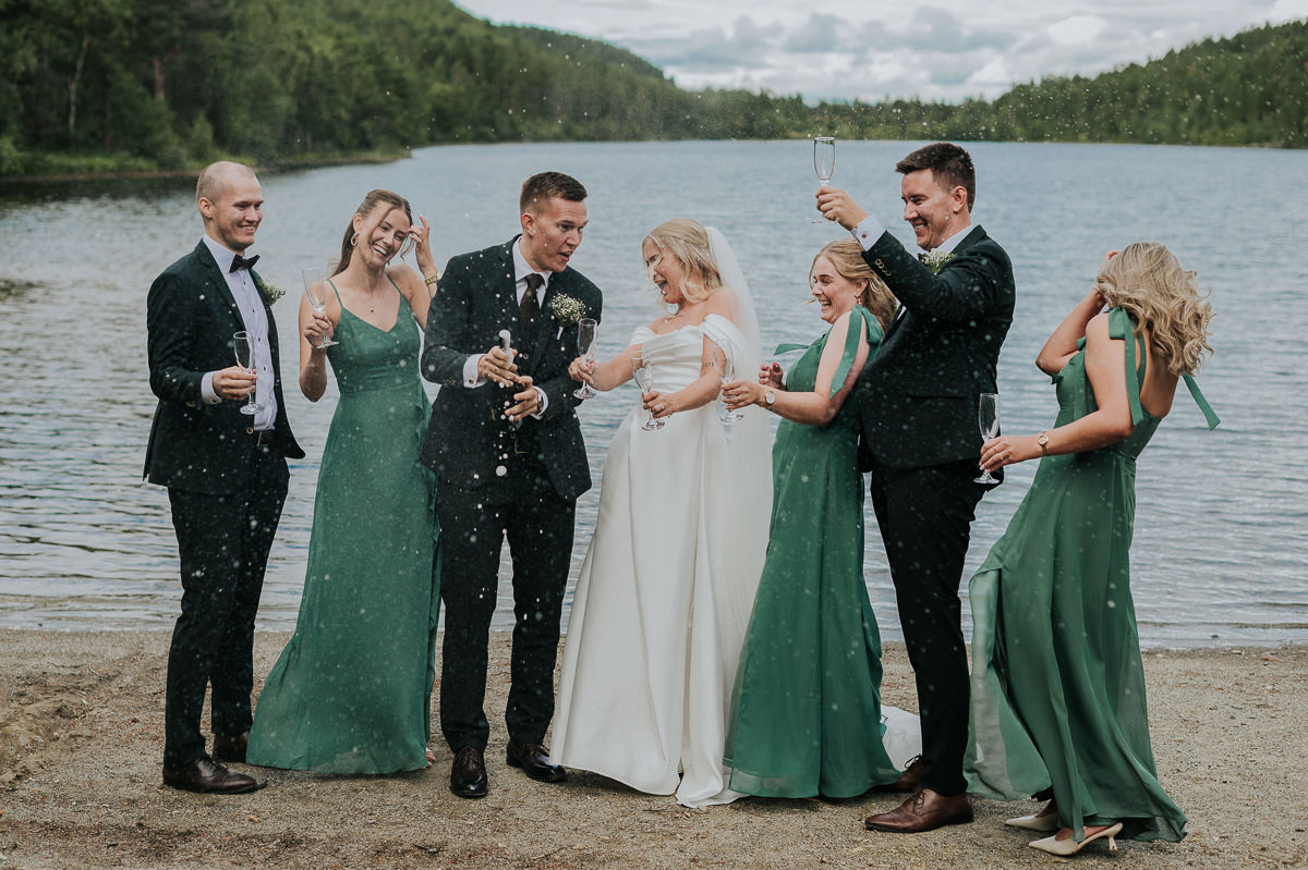 Brudepar og forlovere spretter opp en flaske champagne på en bryllupsdag i Alta