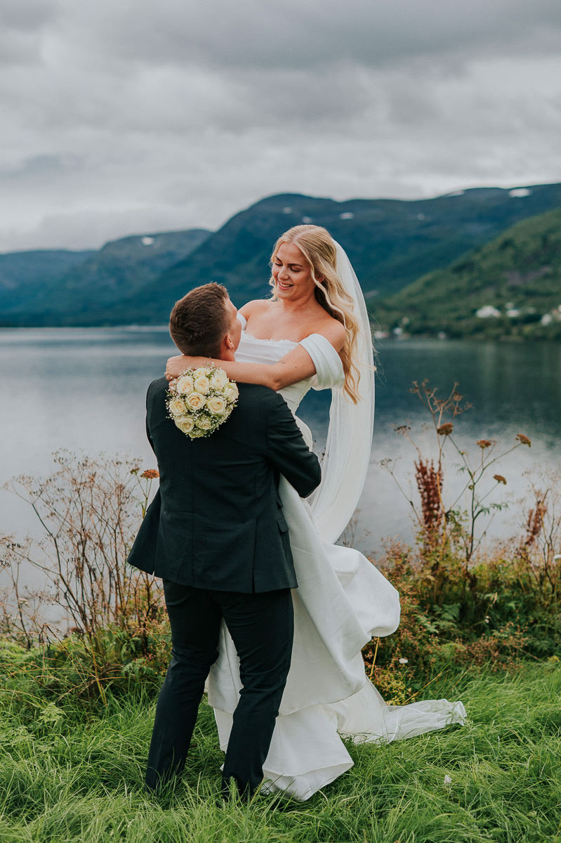 Et elegant bryllup i Alta - brudeparet tar brudeparbildene med en fjordutsikt på en nydelig sommerdag