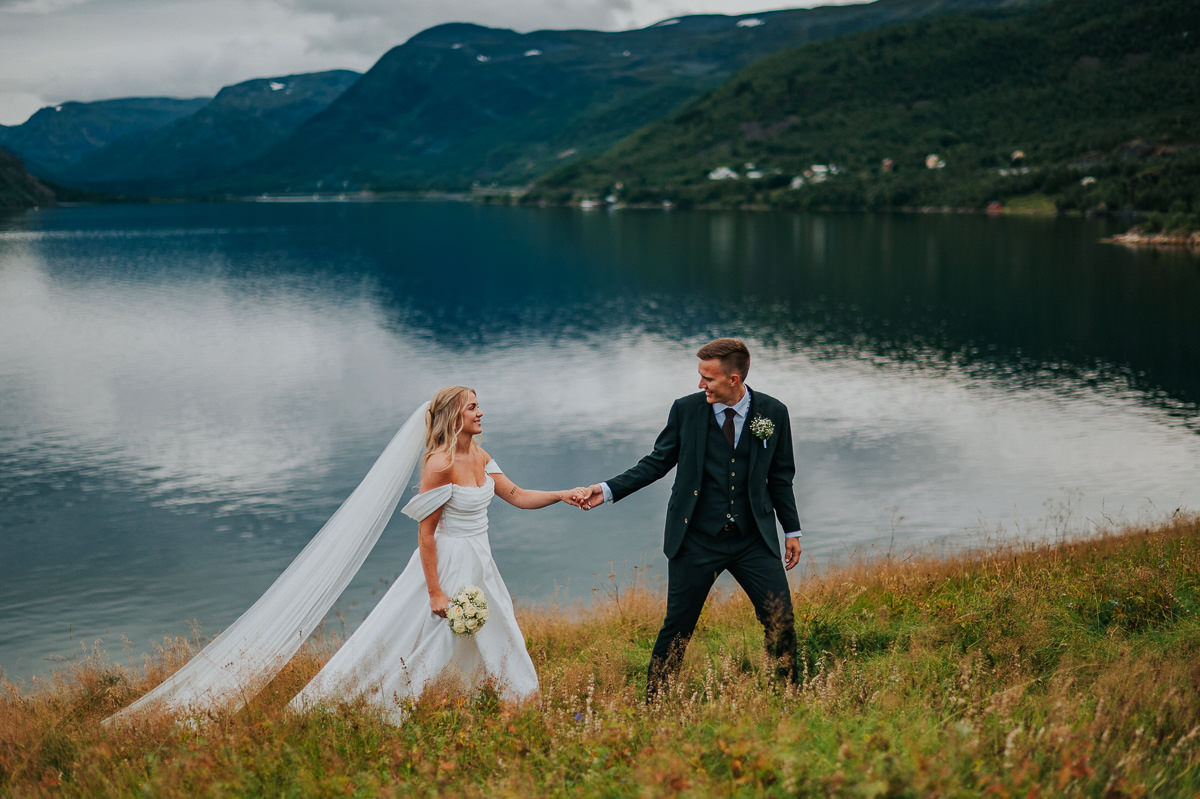 Et elegant bryllup i Alta - brudeparet tar brudeparbildene med en fjordutsikt på en nydelig sommerdag