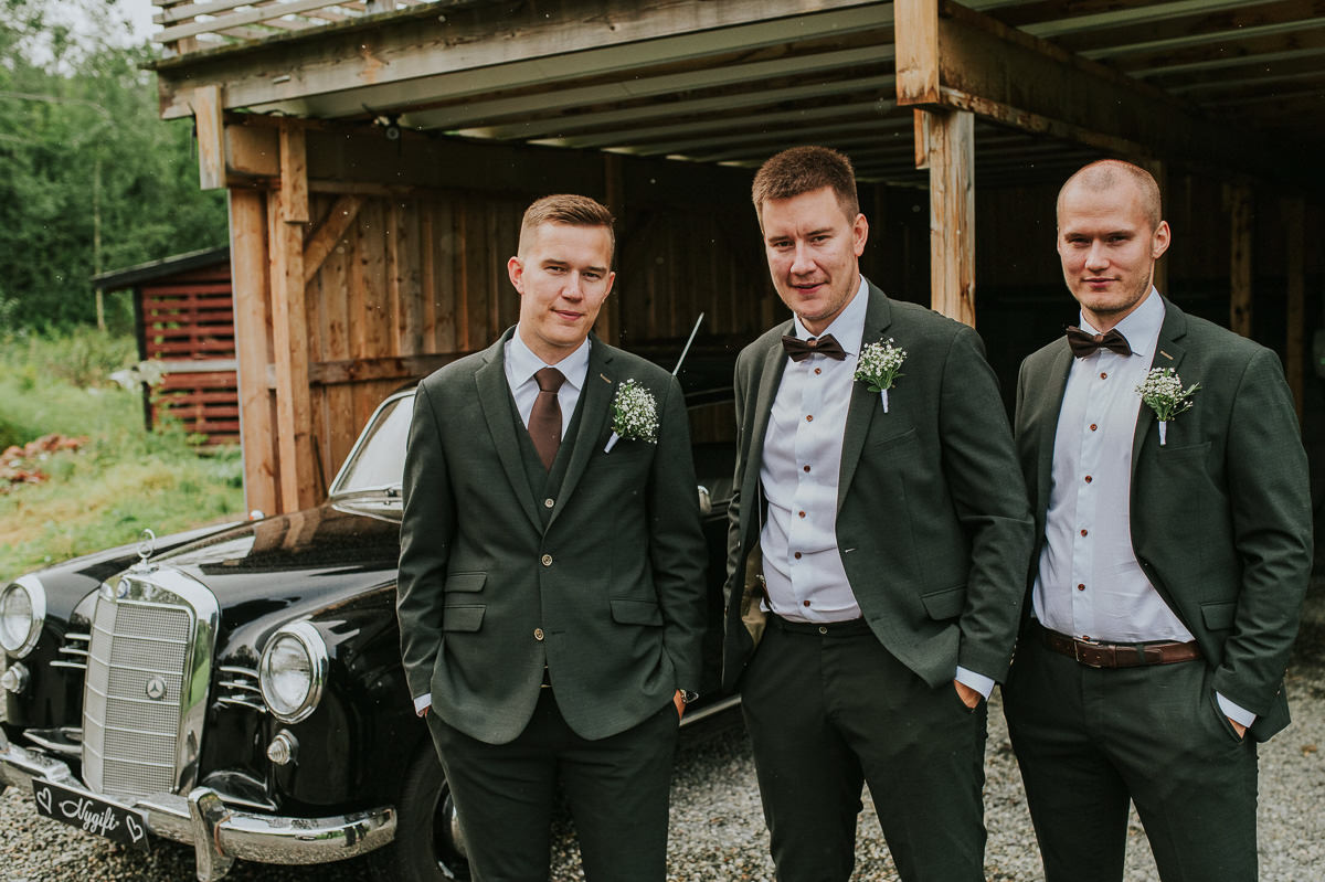 Brudgommen poserer foran en retro bil sammen med sine forlovere