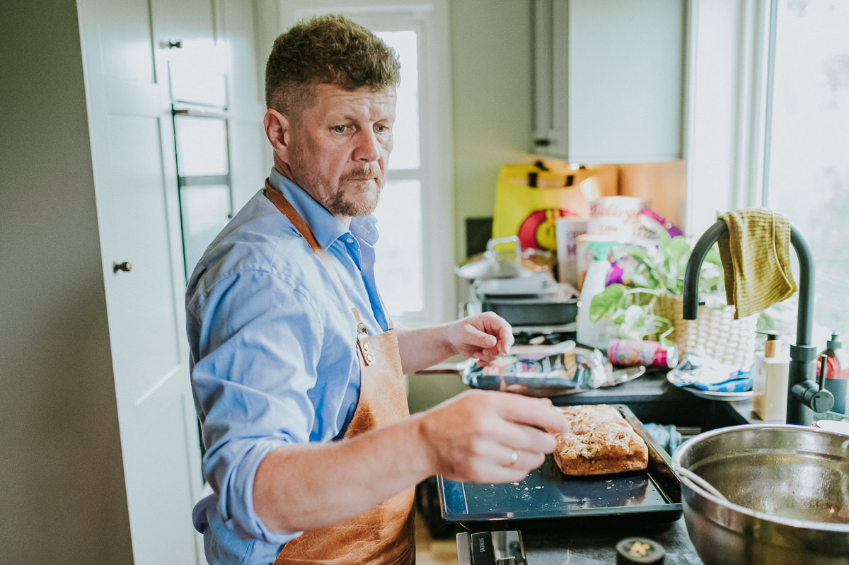 En mann i blå kjorte lager mat på kjøkkenet