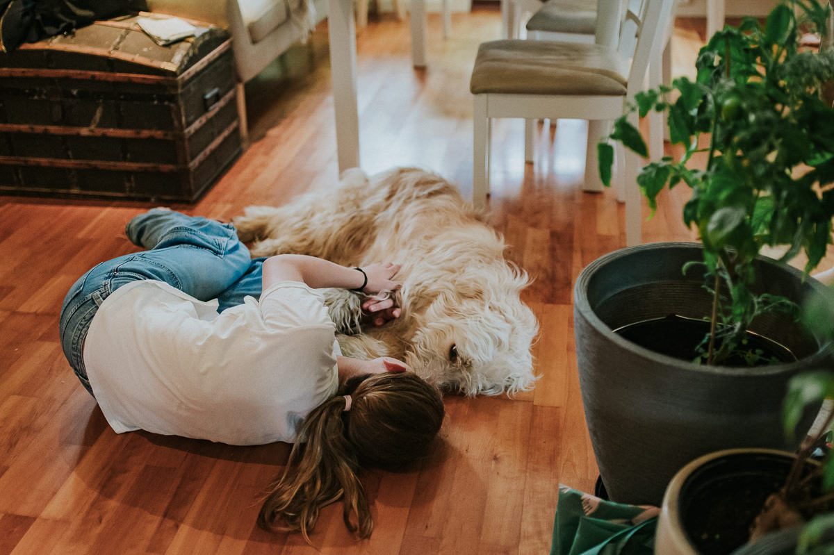 En jente ligger på gulvet sammen med en hund 