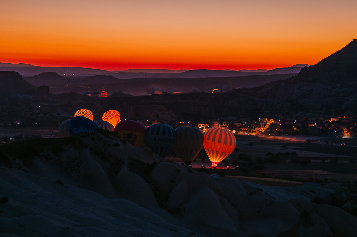 Gorgeous dawn photograph of hot air balloons before sunrise in Cappadocia Turkey with red and purple sky