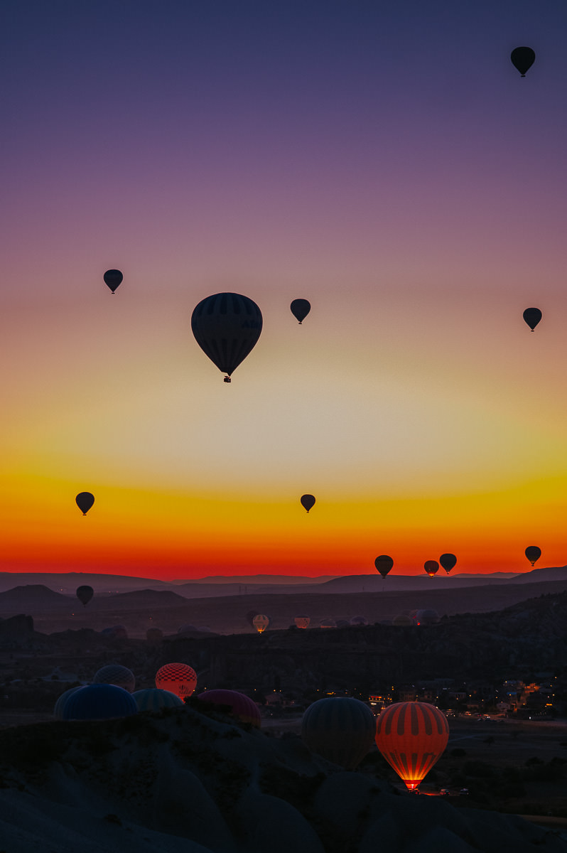Gorgeous dawn photograph of hot air balloons before sunrise in Cappadocia Turkey with red and purple sky