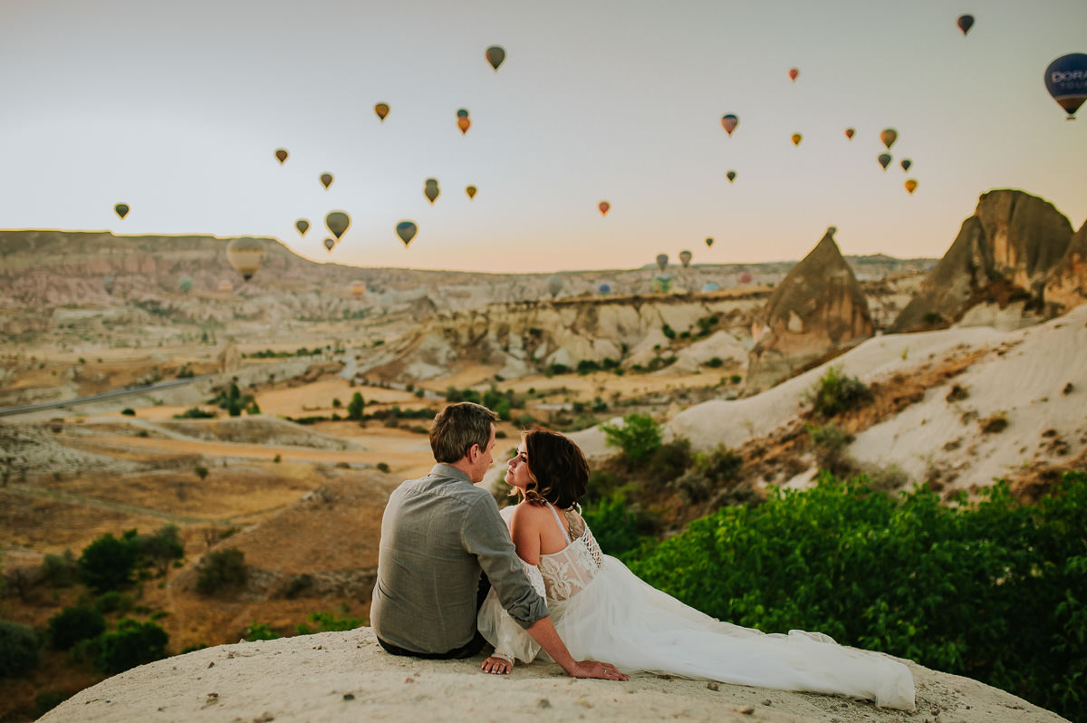 Bride and groom at dawn in Cappadocia watching hot air balloons drift in the sky on the day of their Cappadocia elopement in Turkey - captured by Europe elopement photographer TS Foto Design