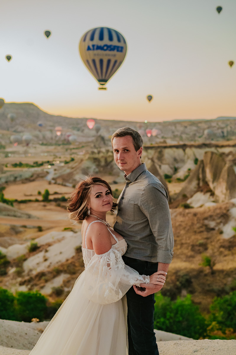 Bride and groom at dawn in Cappadocia watching hot air balloons drift in the sky on the day of their Cappadocia elopement in Turkey 
