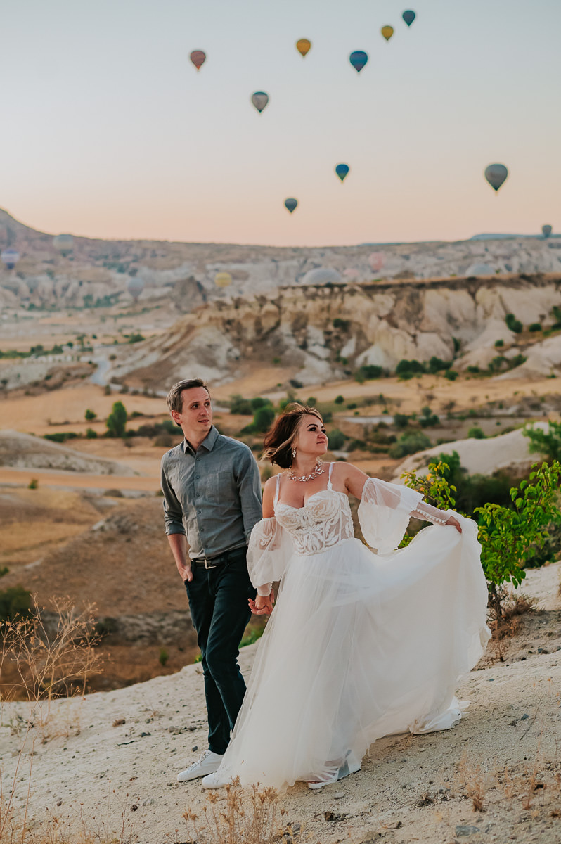 Bride and groom at dawn in Cappadocia watching hot air balloons drift in the sky on the day of their Cappadocia elopement in Turkey 