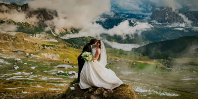 Epic Seceda elopement in the Dolomites - bride and groom kissing on the mountaintop surrounded by rolling clouds and gorgeous light