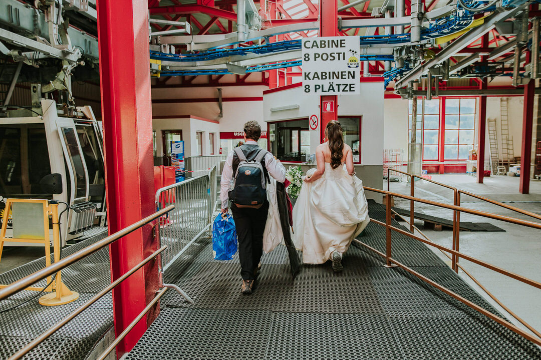 Bride and groom walking towards cable car in Col Raiser for the Seceda hike on the day of their adventure elopement in the Dolomites