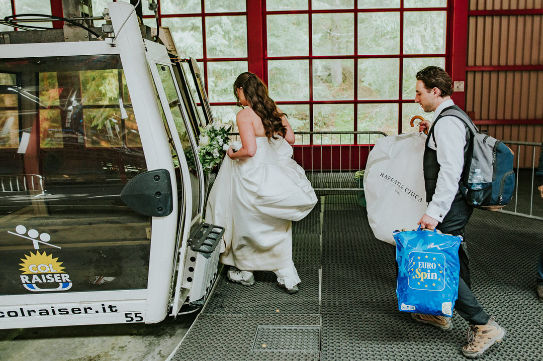 Bride and groom walking towards cable car in Col Raiser for the Seceda hike on the day of their adventure elopement in the Dolomites