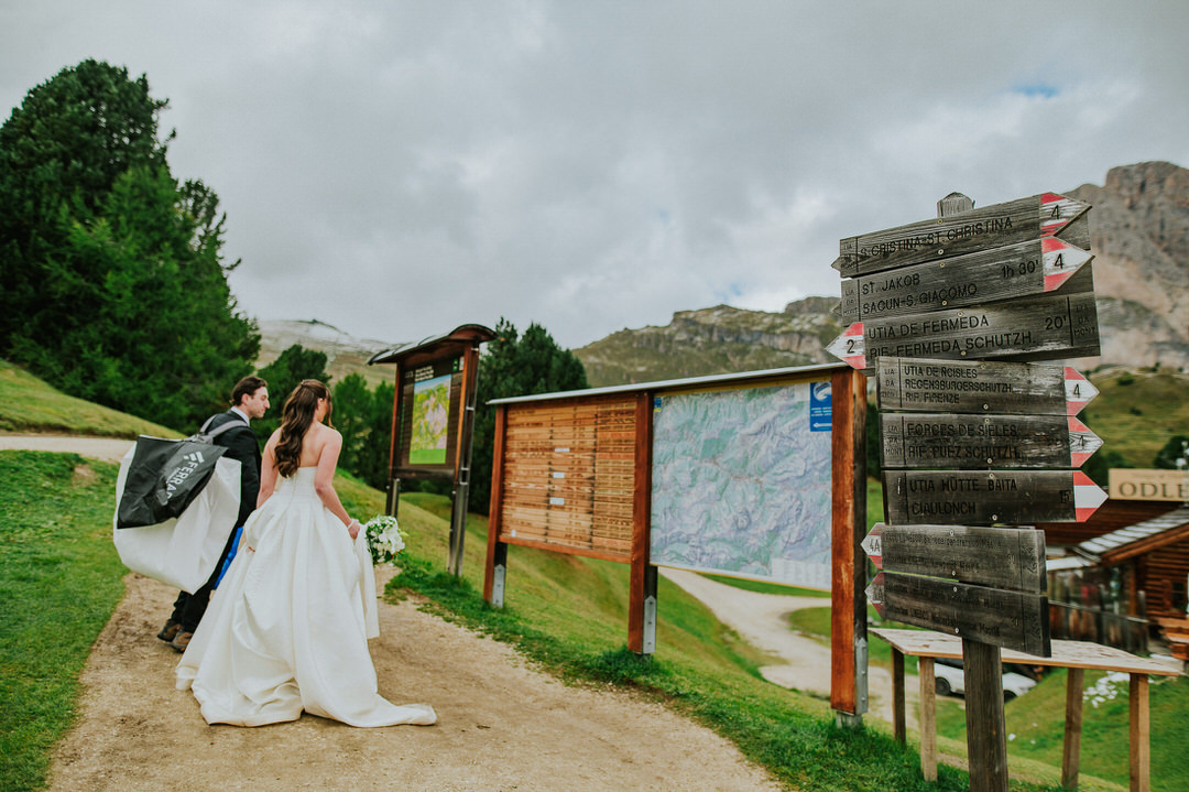 Bride and groom in their wedding attire hiking up the trail in the Italian Dolomites for their fall Seceda elopement 