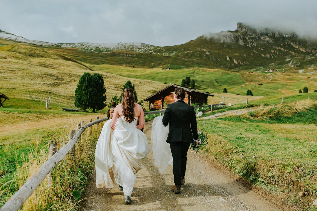 A Seceda elopement in the Italian Dolomites - beautiful bride and groom walking among stunning landscapes - captured by Dolomites elopement photographer TS Foto Design