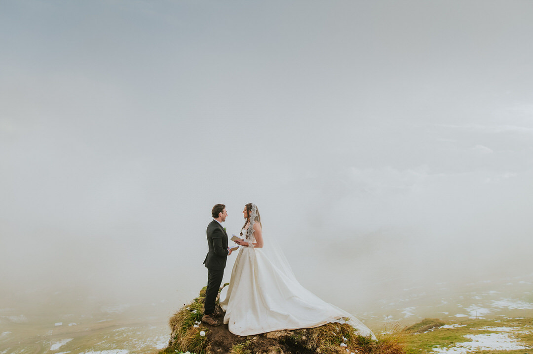 Seceda elopement in the Italian Dolomites - bride and groom reading their vows to each other surrounded by clouds 