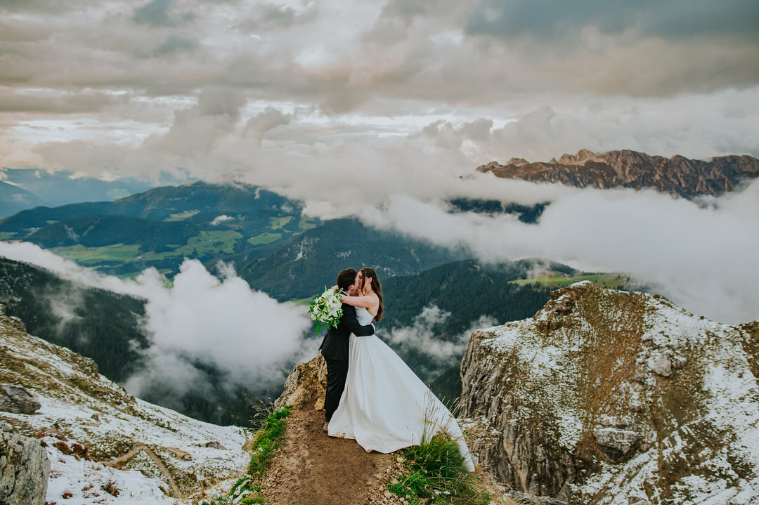 Stunning bride and groom portrait on Seceda mountaintop at sunset with dramatic sky - captured by Dolomites elopement photographer TS Foto Design