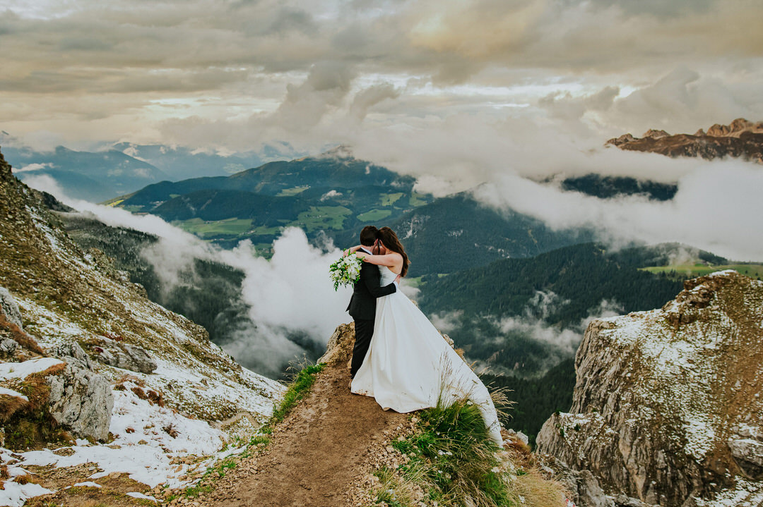 Stunning bride and groom portrait on Seceda mountaintop at sunset with dramatic sky - captured by Dolomites elopement photographer TS Foto Design