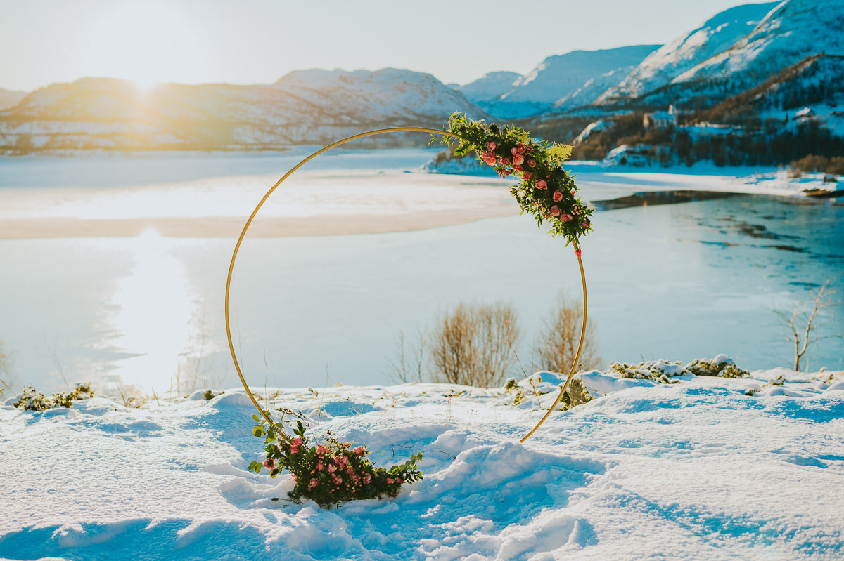 Stunning circular wedding arch decorated with roses and greenery in front of an Arctic winter landscape in Alta Norway