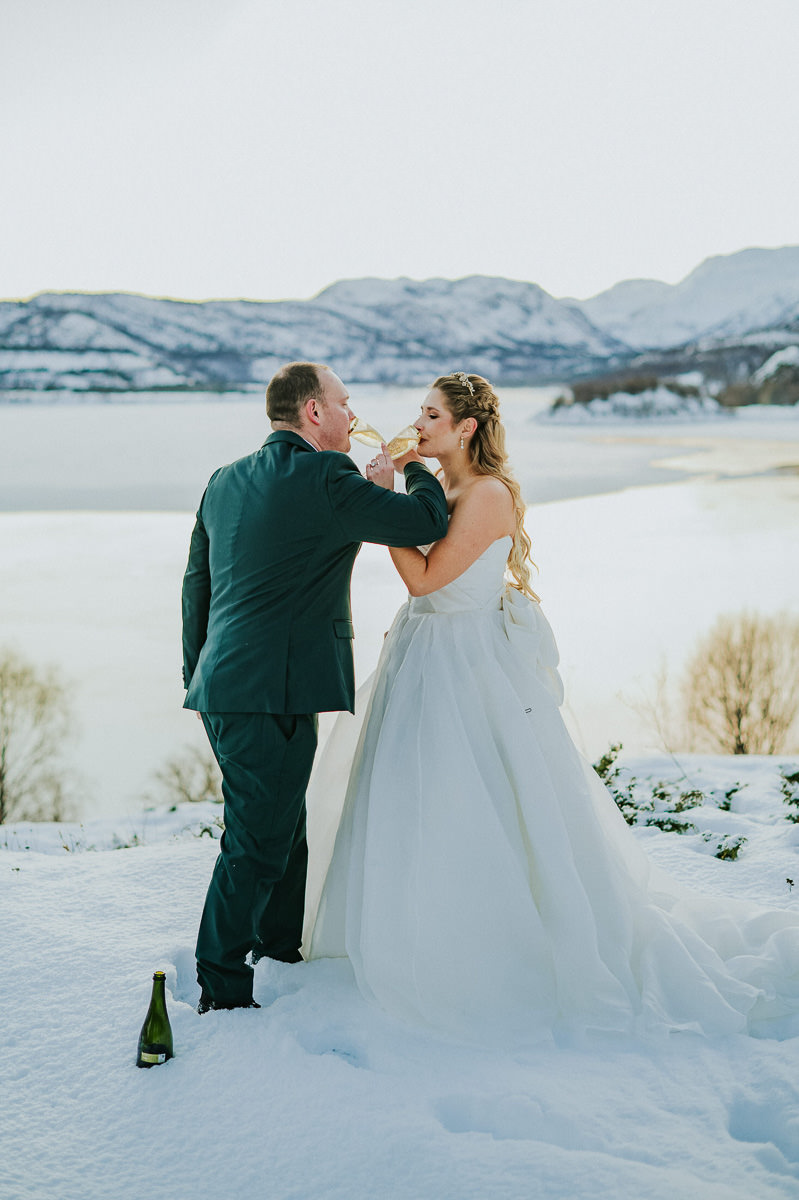 Bride and groom doing a champagne toast on the day of their winter elopement in Alta Norway 