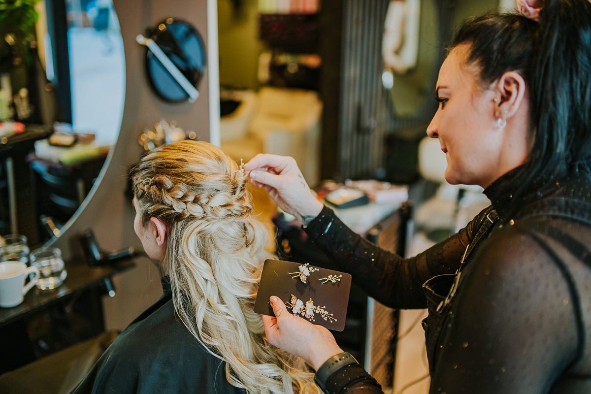 Gorgeous bride getting ready at a hair salon in Alta Norway - she has a braid hair style with pearls in her blond wavy hair