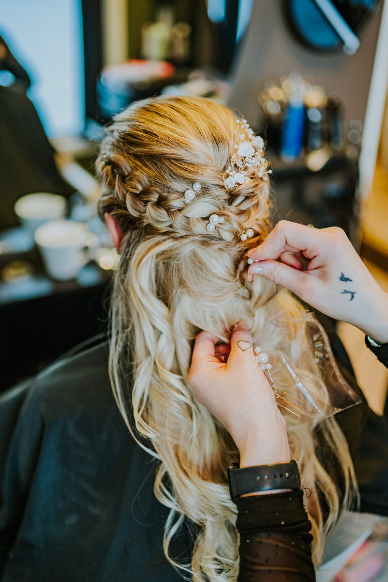 Gorgeous bride getting ready at a hair salon in Alta Norway - she has a braid hair style with pearls in her blond wavy hair