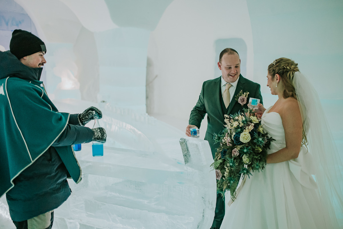 Bride and groom drinking blue drink from a glass made of ice in the igloo hotel Sorrisniva in Alta Norway