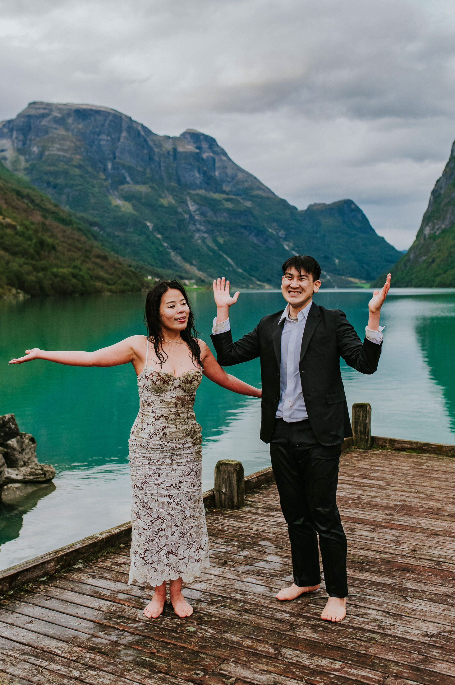 Bride and groom in wet wedding attire smiling after a jump in a glacier lake in Norway