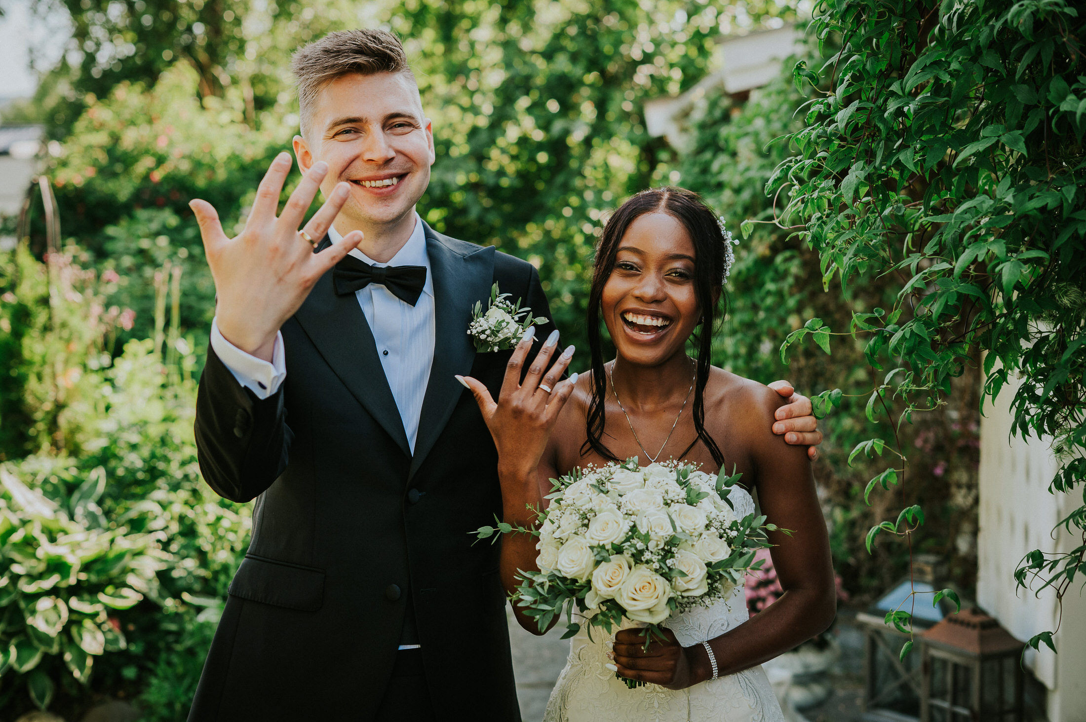 Happy bride and groom smiling to the camera and showing their wedding rings
