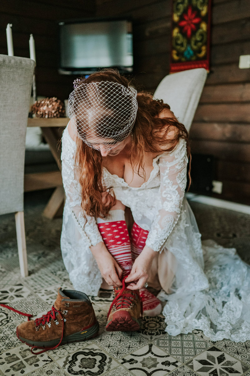 Bride putting on her adventure elopement hiking boots with red laces