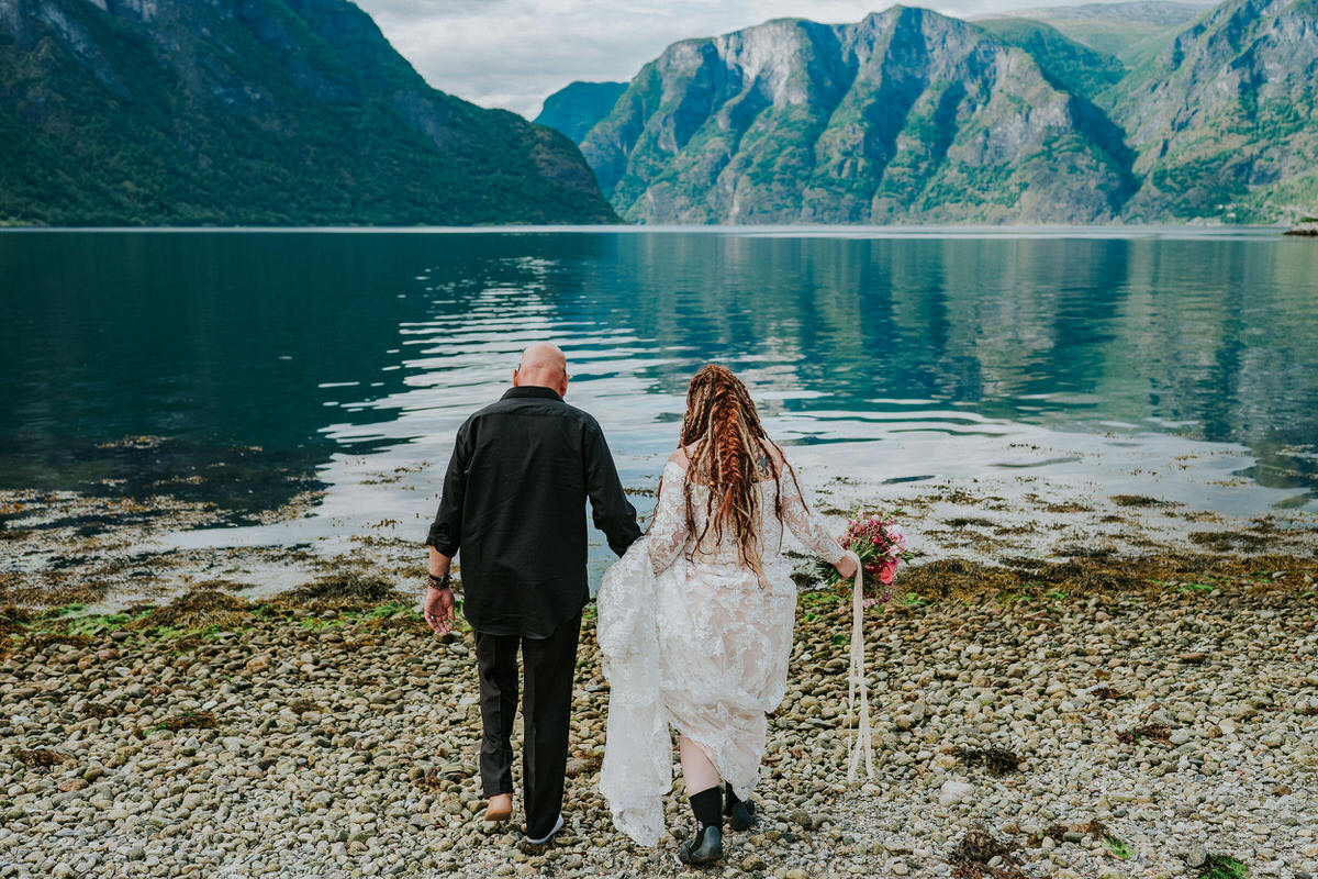 Bride and groom walking into the waters of Aurlandsfjord on the day of their adventure wedding