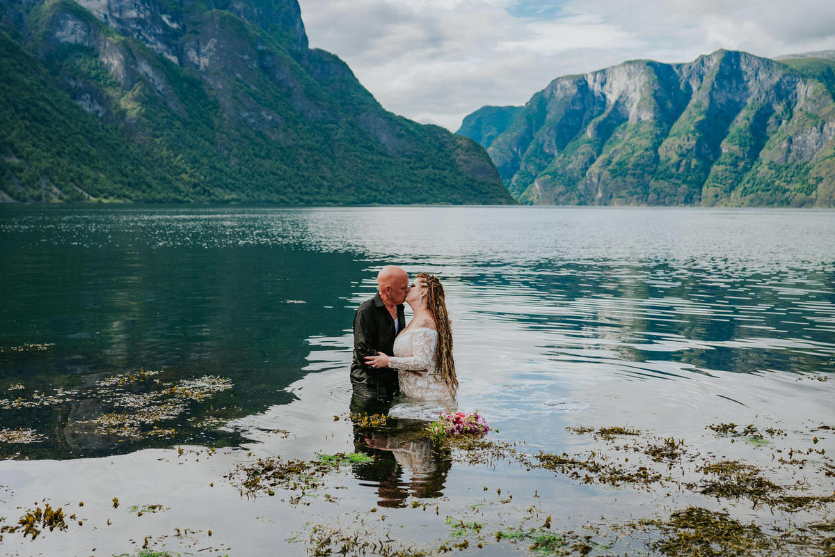 Bride and groom walking into the waters of Aurlandsfjord on the day of their adventure wedding