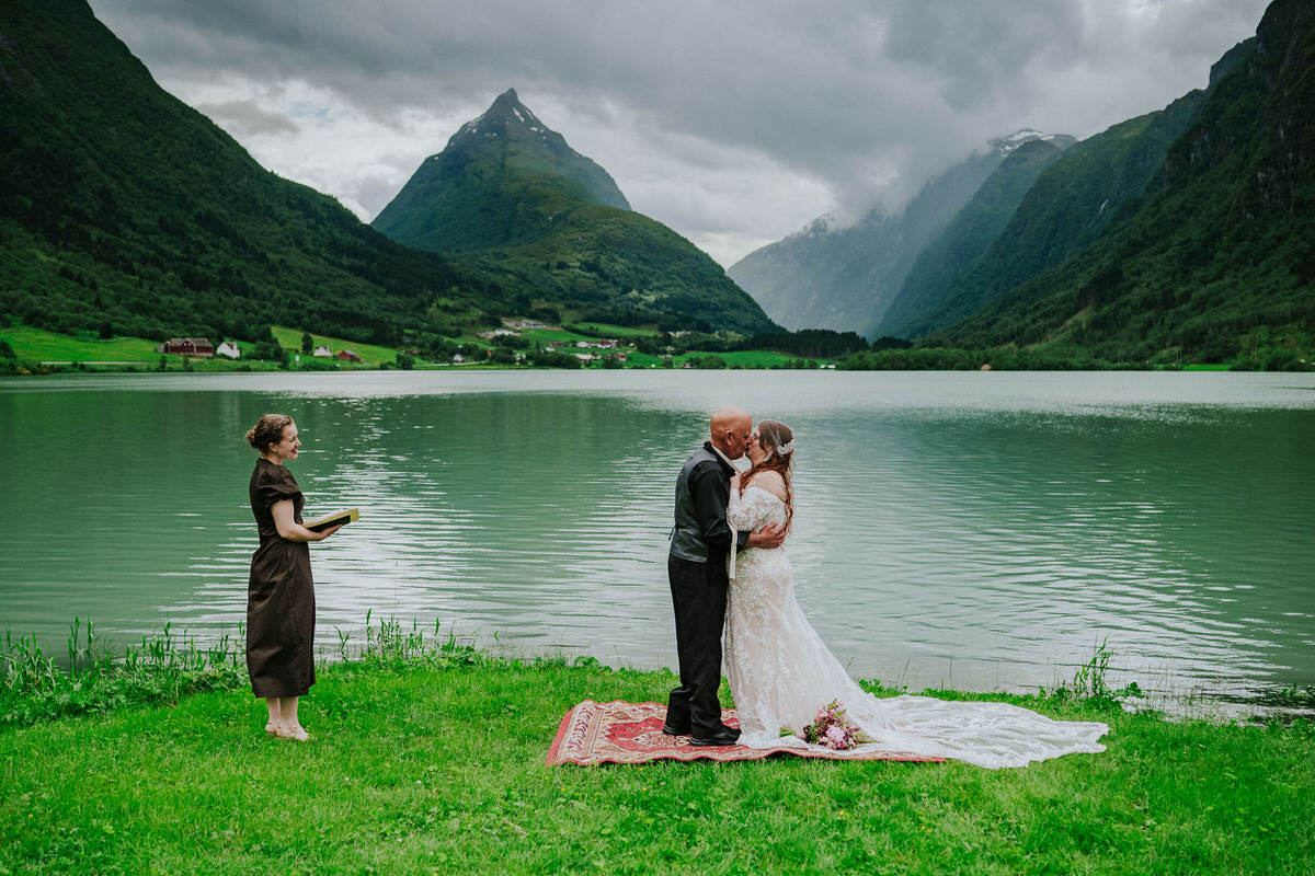 Outdoor elopement ceremony in front of a lake and Mt. Eggenipa in Western Norway - bride and groom kissing