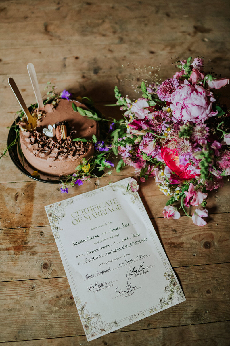 Wedding certificate, bouquet and the chocolate cake decorated with wild flowers