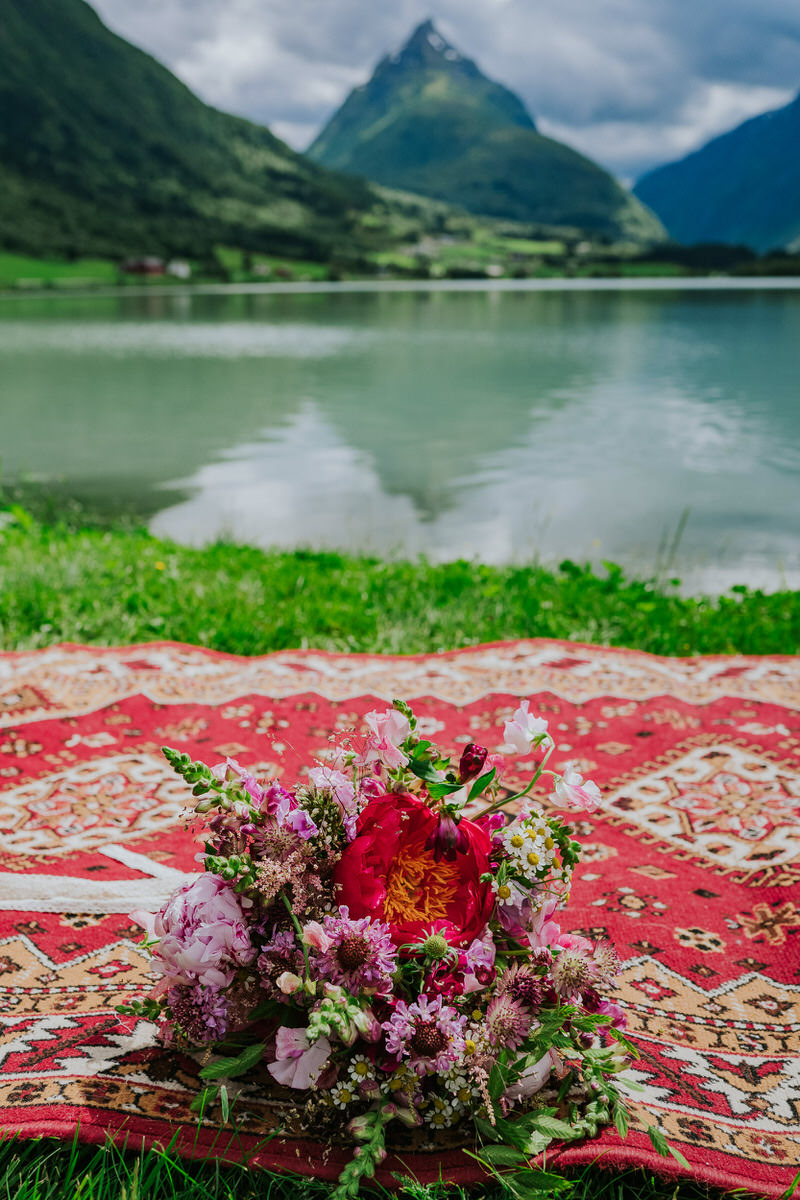 Beautiful purple and burgundy wedding  bouquet photographed outside in front of a mountain view in Norway