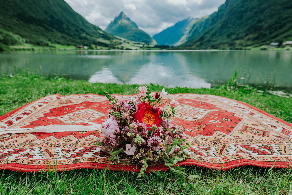 Beautiful purple and burgundy wedding  bouquet photographed outside in front of a mountain view in Norway