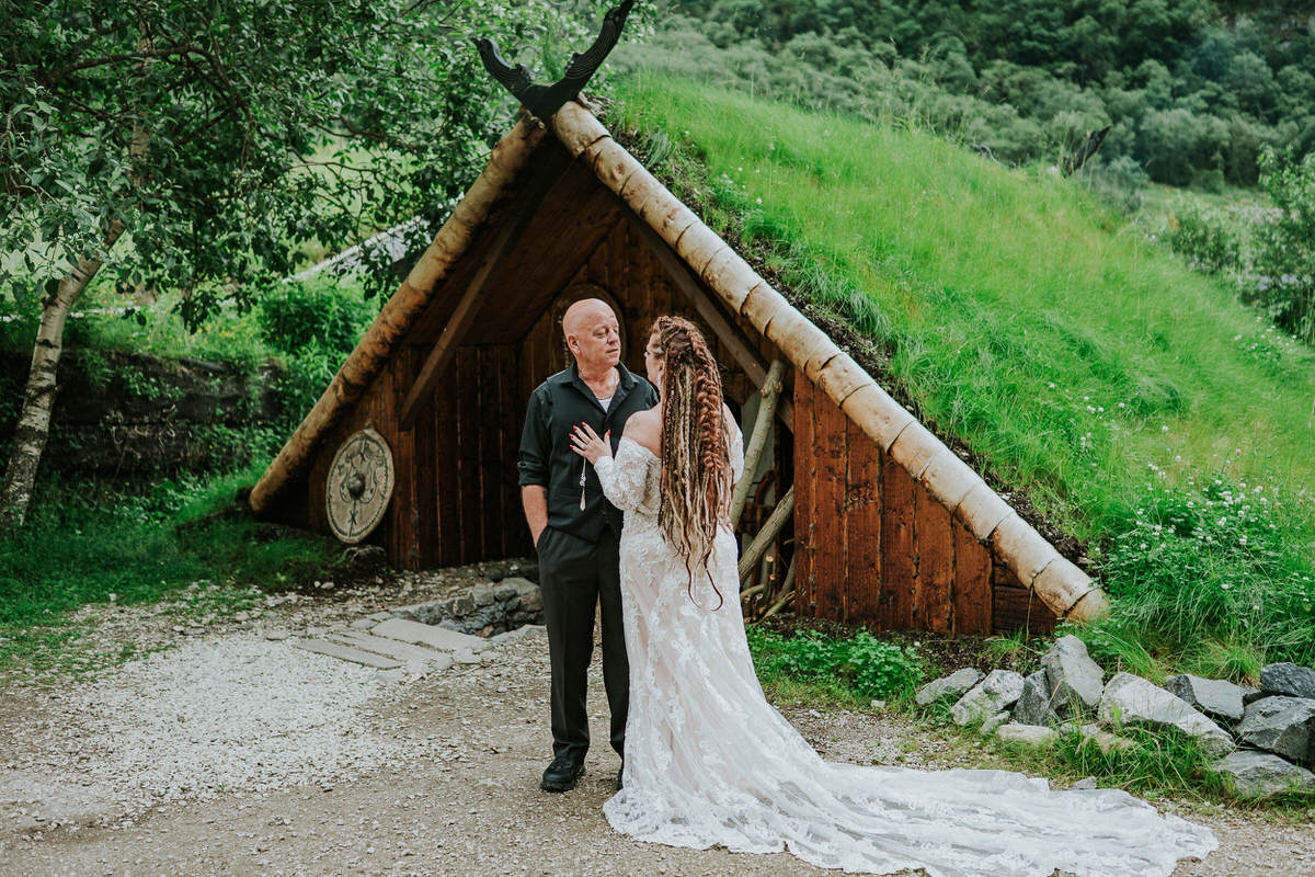Bride and groom posing in front of a viking hut in Gudvangen on the day of their Viking elopement in Norway