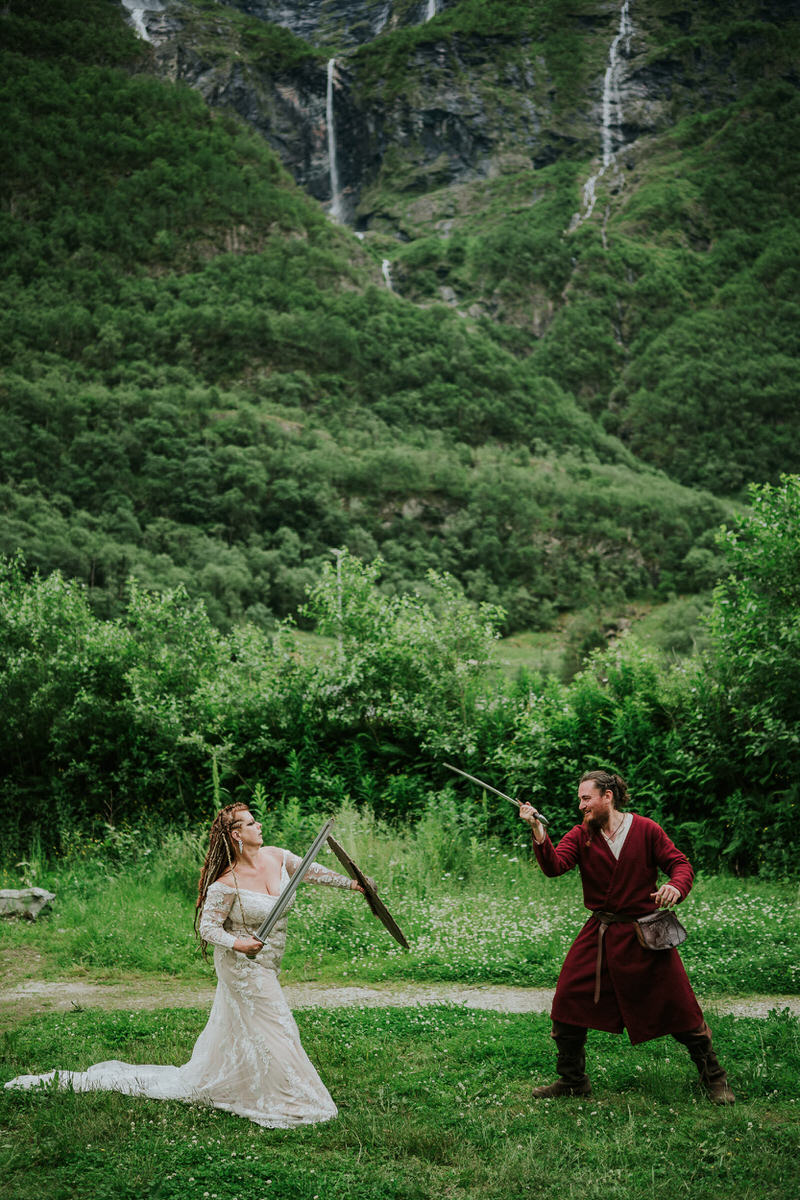 Bride with viking-inspired hair style and braids fighting a viking in Njardarheimr Gudvangen Norway