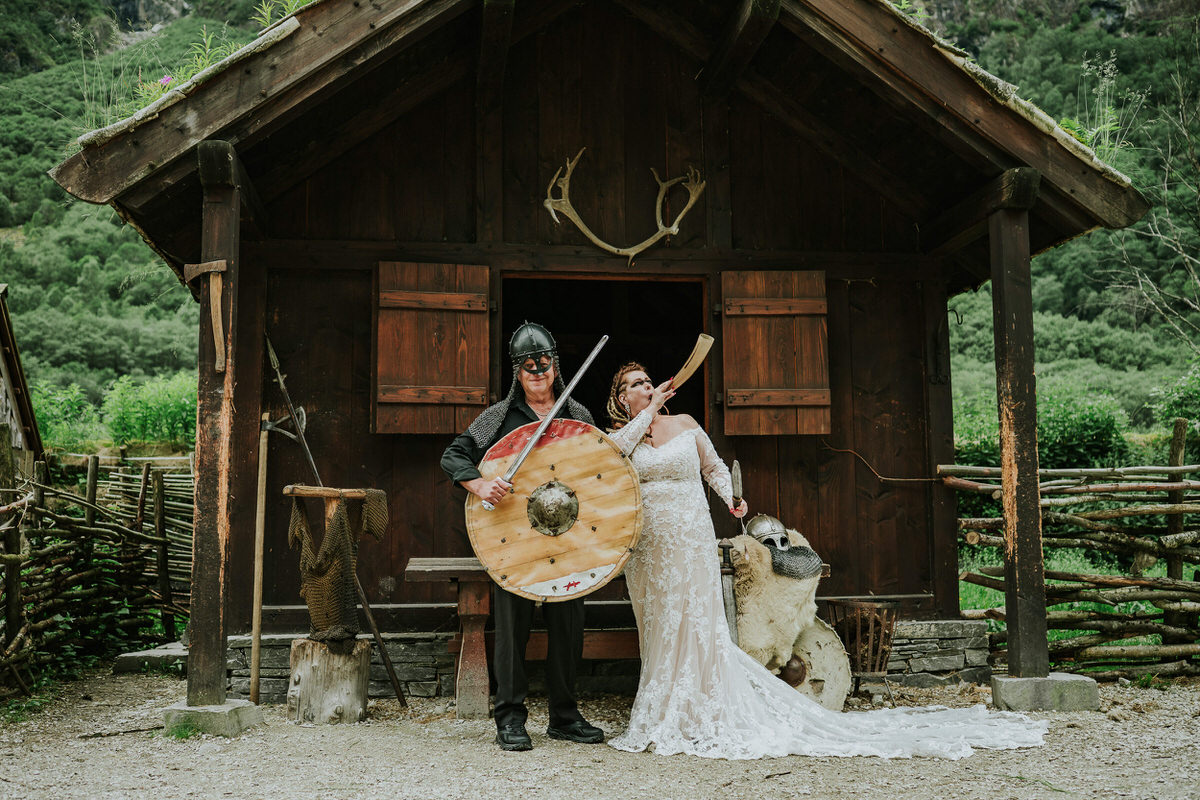 Bride and groom posing in front of a viking hut in Gudvangen on the day of their Viking elopement in Norway
