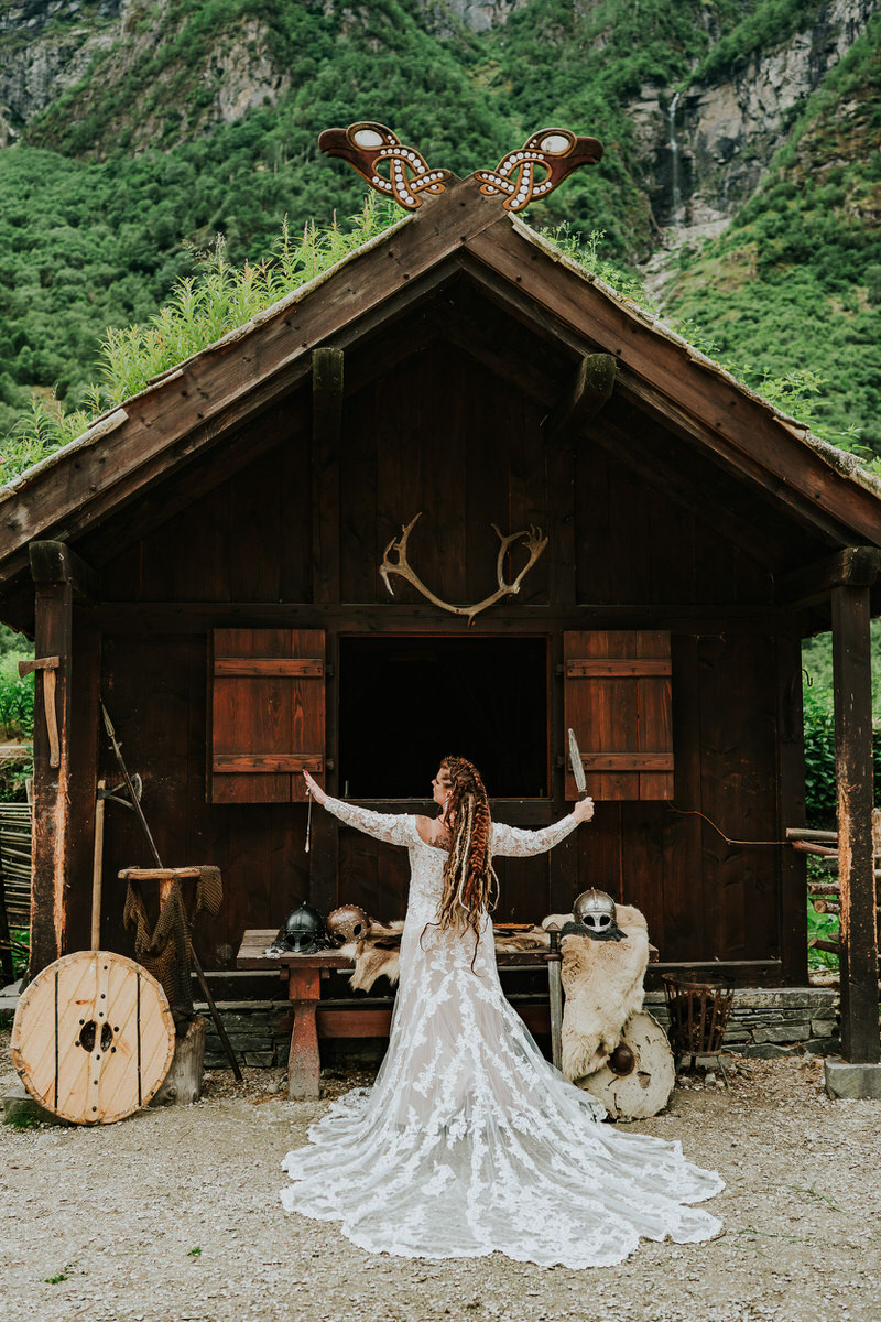 Bride holding a pendulum in front of a viking house in Gudvangen viking village