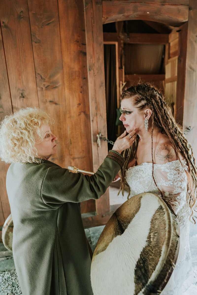 Bride with viking style hair braids playing drums in the viking village in Gudvangen Norway on the day of her viking wedding