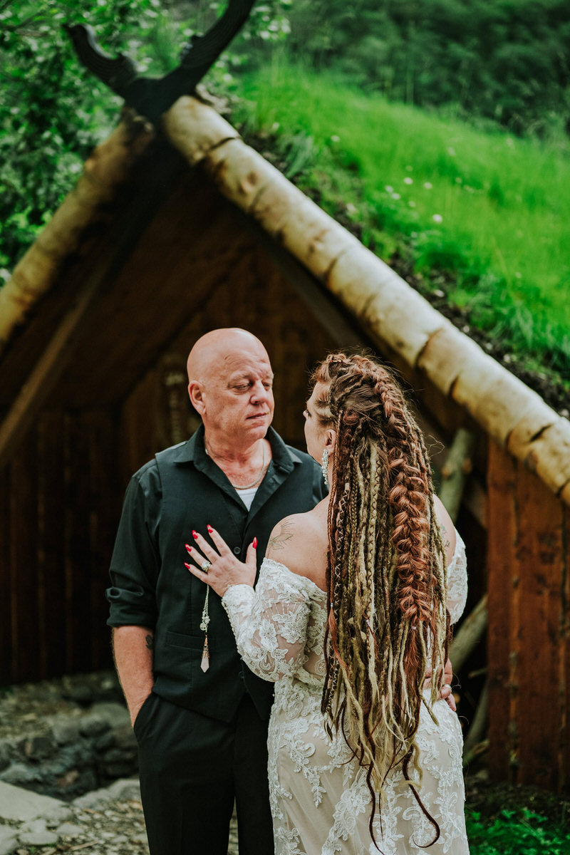 Bride and groom posing in front of a viking hut in Gudvangen on the day of their Viking elopement in Norway